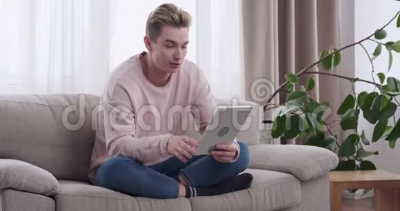 家中数码平板电脑上轻松的男人视频会议视频的预览图