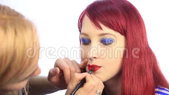 设计师用一支红色铅笔画出模特嘴唇轮廓化妆师用刷子在女人身上涂口红视频的预览图