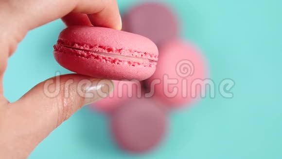 一个女人手里拿着一份粉红色的法式甜点令人兴奋的粉彩背景视频的预览图