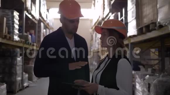 两位在仓库戴着安全帽的同事在讨论与平板电脑的工作时握手视频的预览图