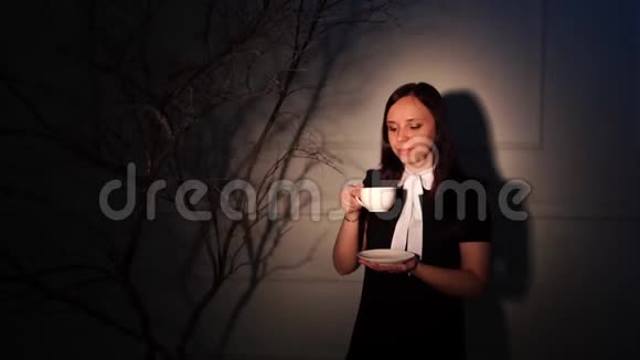 一个穿着优雅衣服的女人在黑暗的房间里喝咖啡性感的女性头发风格拿着一杯咖啡视频的预览图