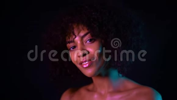 黑人背景下年轻漂亮的非裔美国女孩迷人的女人完美的妆容看着相机微笑着视频的预览图