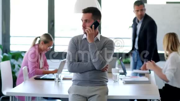英俊的年轻商人在同事间用手机聊天视频的预览图