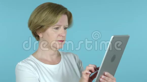老女人对蓝底平板电脑损失的反应视频的预览图