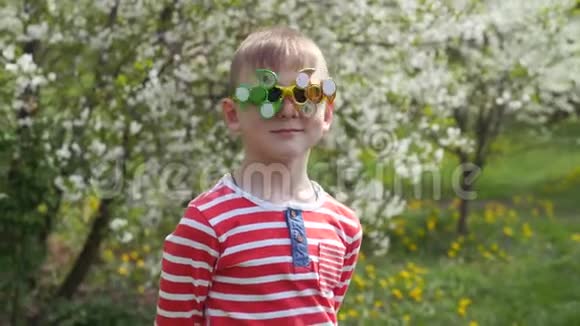 眼镜上的旋转器在旋转在街上玩得很开心一个孩子在樱花盛开的背景下视频的预览图