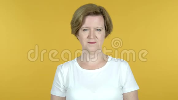 老女人在黄色背景下的胜利标志视频的预览图
