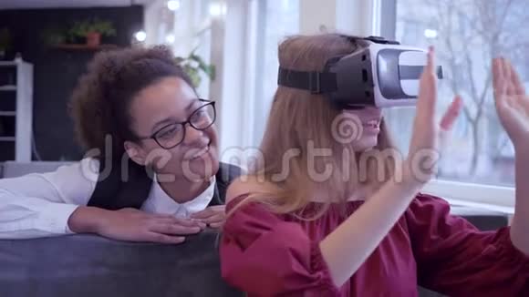 现代娱乐欢笑混合种族朋友女孩玩虚拟现实使用特殊的VR头盔特写在咖啡馆视频的预览图
