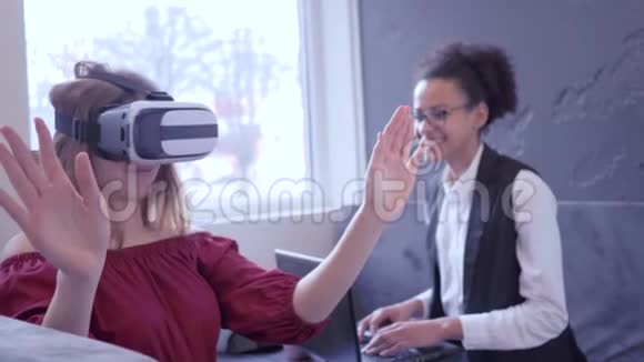 技术VR开朗的多民族女友使用VR眼镜和现代计算机技术进行游戏虚拟现实视频的预览图