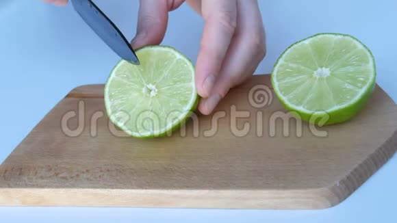女人的手在白色的桌子上切下成熟的青柠家里的木制厨房板视频的预览图