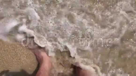 沙滩上的雄性脚在浅水中暑假背景从上面缩短视频的预览图