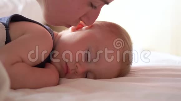 妈妈吻着婴儿的脸颊而他却以缓慢的动作甜蜜地睡觉视频的预览图