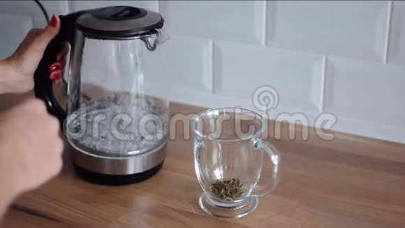 女人泡茶女孩用水壶把水倒进杯子里视频的预览图