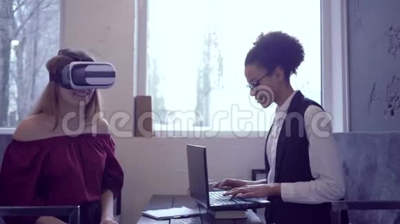虚拟现实游戏快乐混血朋友女孩使用VR耳机和现代笔记本电脑技术玩虚拟现实视频的预览图