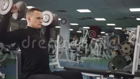 健身馆里的肌肉男把坐在长凳上的重物举起视频的预览图