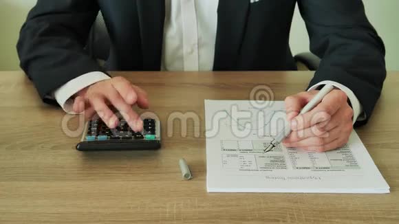 商人在办公室用4K的木桌检查计算器的计算结果视频的预览图