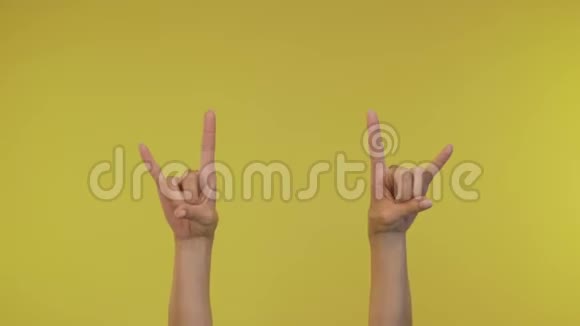 女人的手在黄色背景下显示摇滚手势视频的预览图