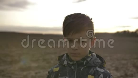 愤怒的悲伤男孩在日落时看镜头的肖像视频的预览图