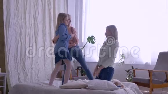 一家人被愚弄疯狂的女孩女儿一边在家里的床上娱乐一边为快乐的妈妈唱歌跳舞视频的预览图
