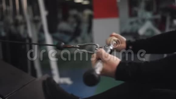 一个年轻的健康人在健身房的机器上训练从侧面特写视频的预览图