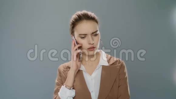 在演播室里用灰色背景的手机聊天的女人视频的预览图