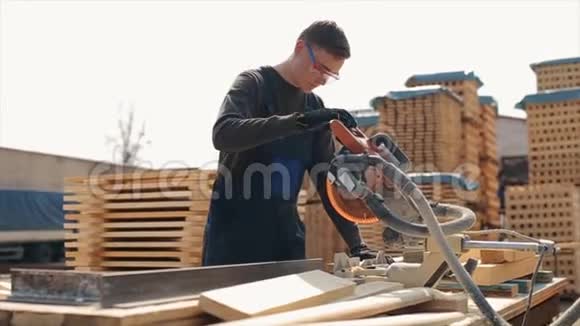 关闭一名年轻木工工人佩戴施工护目镜并使用木切割机均匀英译汉视频的预览图