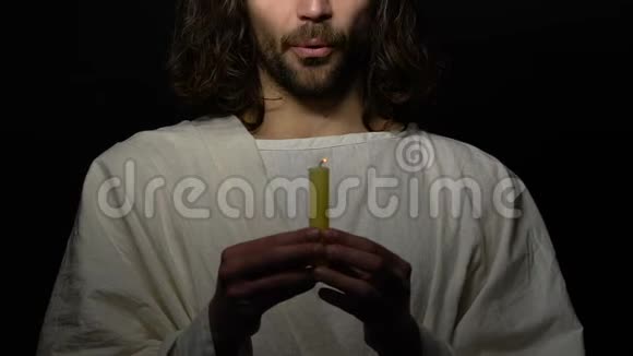 穿长袍的男罪犯在黑暗的背景上情绪化地吹蜡烛拒绝上帝视频的预览图