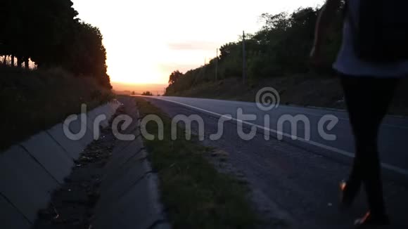 日落时分在柏油路附近散步的年轻人剪影视频的预览图