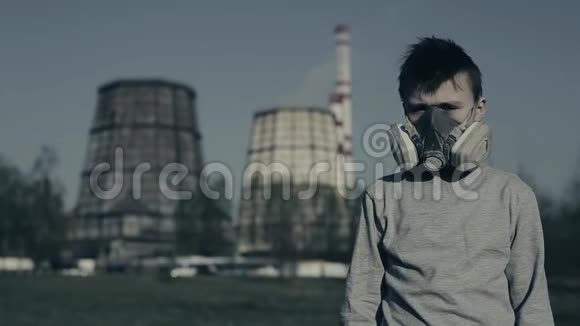 戴着面具的青少年男孩在防毒面具呼吸器上对工业吸烟管采取特写空气污染视频的预览图