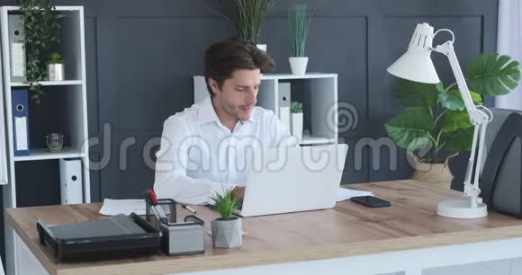 在办公室做文书工作和使用笔记本电脑的商人视频的预览图