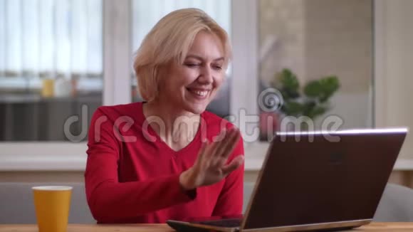 在一间舒适的公寓里一位在笔记本电脑上打着视频电话的白种人女人在室内开心地笑着的特写镜头视频的预览图