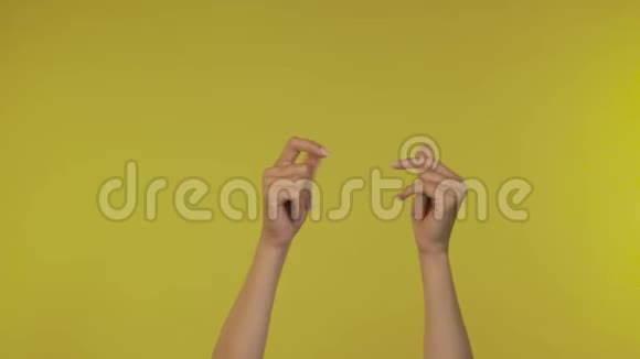 女人的手拍她的手指音乐节奏手势孤立在黄色背景在工作室复制空间视频的预览图