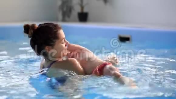 可爱的小男孩和他妈妈在游泳池里玩视频的预览图