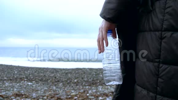 特写镜头一个女人在海滩上扔了一个空的塑料瓶视频的预览图