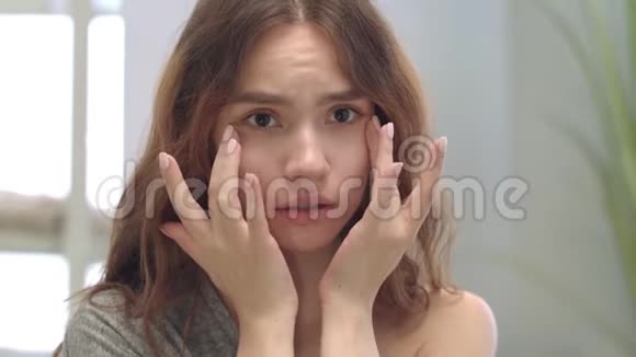 不满意的女人在浴室镜子里摸脸问题皮肤概念视频的预览图