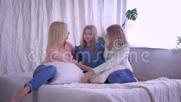 爱的家庭肖像幸福的微笑女孩与心爱的母亲拥抱坐在床上视频的预览图