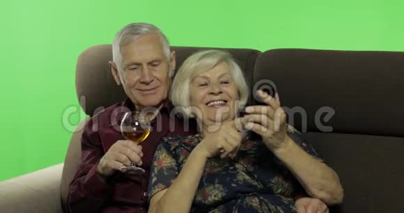 年长的男人和女人坐在沙发上在智能手机上工作视频的预览图