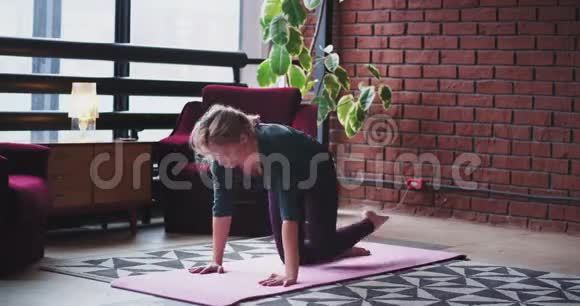 她在家里客厅里练习瑜伽穿着舒适的运动服在垫子上视频的预览图