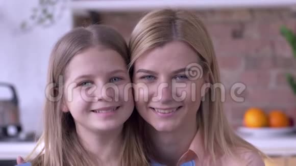 有爱心的姐妹可爱的蓝眼睛的小女孩和成年女孩的画像正微笑着看着家里的摄像机视频的预览图