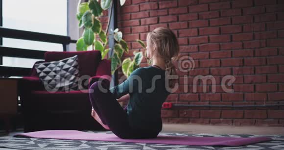 早上好一位练习瑜伽的女士她伸展双腿坐在垫子上做一个艰苦的练习视频的预览图