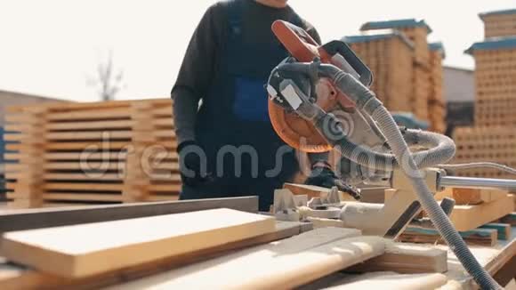 关闭一名年轻木工工人佩戴施工护目镜并使用木切割机均匀英译汉视频的预览图
