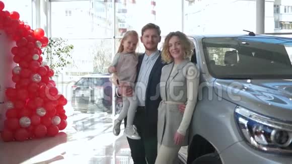 幸福的消费家庭夫妇和小女孩在手上的肖像展示了在汽车陈列室购买的汽车钥匙视频的预览图