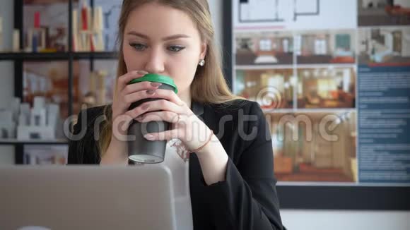 女室内设计师喝咖啡在办公室里工作手提电脑视频的预览图