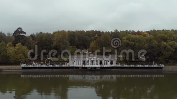 镜头飞过水面朝着一家美丽的白色餐厅飞去一个码头矗立在森林上空中飞行视频的预览图
