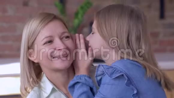 快乐的母亲微笑的小女孩告诉心爱的妈妈在家里耳边低语秘密视频的预览图
