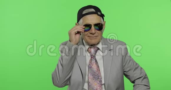戴着太阳镜和帽子的有趣的老商人微笑着老人眨眼视频的预览图