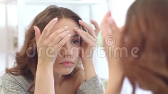 一个年轻的少女在沐浴室的正面镜子上挤压皮肤视频的预览图