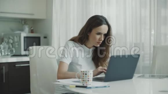 伤心的女人在白色厨房工作笔记本电脑不高兴的人使用电脑视频的预览图