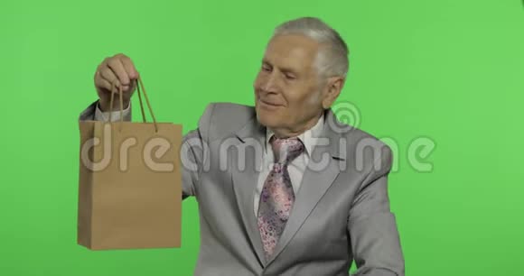 带购物袋的老人看着镜头伸展礼物视频的预览图
