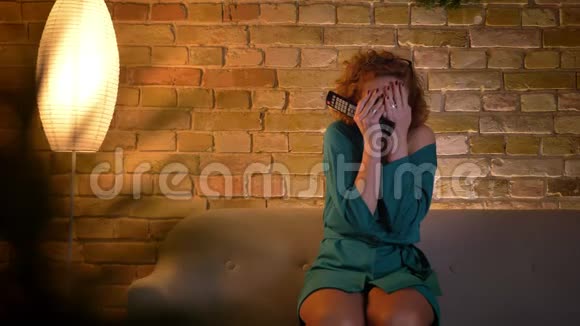 可怕的姜黄色卷发的白种人女孩看恐怖电影的肖像双手捂着舒适的家视频的预览图