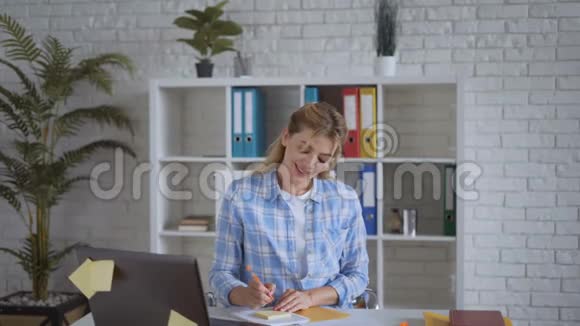 有魅力的商业女性在办公室项目上工作并在笔记本上写想法视频的预览图